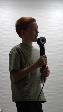A guy sings while holding a hairdryer in his hand instead of a microphone. A teenager improvises in the bathroom with a hairdryer in hand. High quality FullHD footage