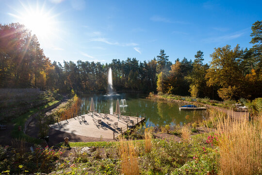 Autumn park lake with fountain, terrace and sunny sky