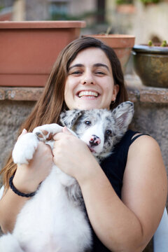 Smiling woman holding a border collie puppy outdoors