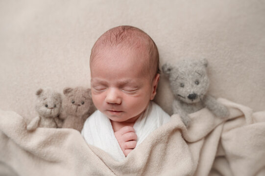 Sleeping newborn baby wrapped in blanket with teddy bears