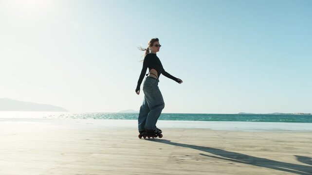 Gimbal push in from wide to medium of young woman skating on sunny beach promenade. Side view, leg raised, ponytail flowing. Turquoise sea, mountains, clear blue sky. Active Mediterranean summer