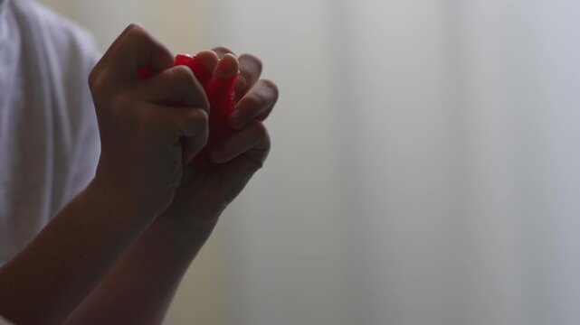 A child plays with homemade red slime. A fun sensory activity, stress relief, fine motor development, and a concept for educational content, toy stores, and home child development. 