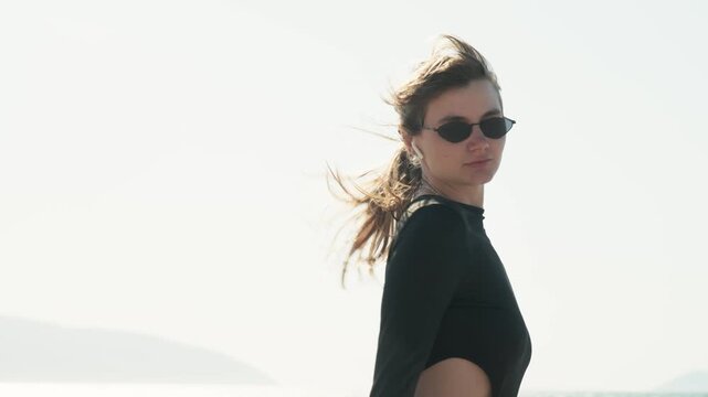 Portrait of young woman riding roller skates outdoors, filmed with stabilizer in smooth motion. Backlit sunlight, wind in hair and minimal background create modern lifestyle and freedom concept.