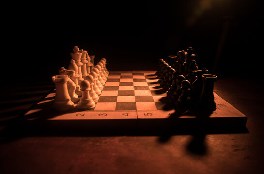 Chess board game concept of business ideas and competition. Chess figures on a dark background with smoke and fog.