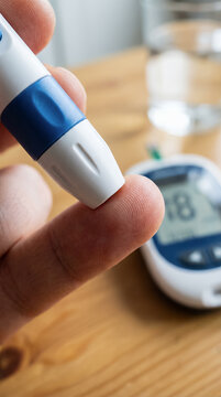 Person of diabetic pricking finger with lancing device to test blood glucose level at home. Insulin-dependent diabetes. Sugar monitoring. Medical with copy-space.