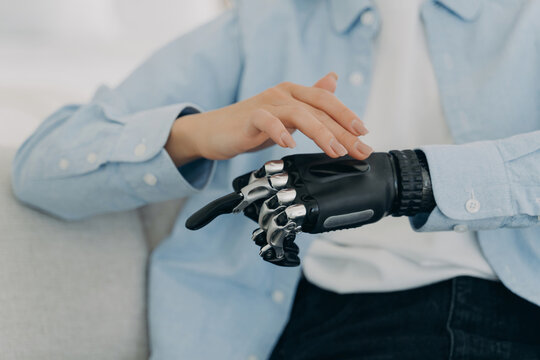 Woman touching prosthetic hand in close up at home