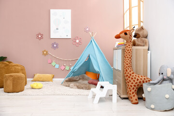 Colorful paper notes and beautiful decor hanging on beige wall near toy wigwam in stylish children's room. Interior design © New Africa