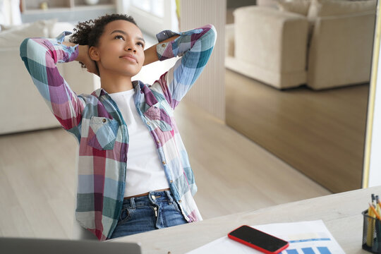 Young black woman taking break at desk while working from home