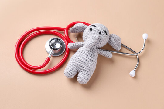 Children's doctor. Stethoscope and toy elephant on beige background