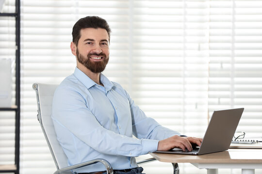 Handsome businessman working on laptop at wooden desk in office