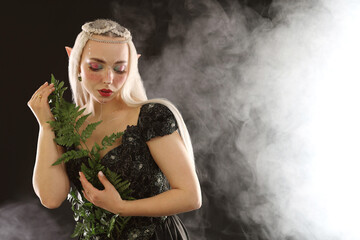 Naklejka premium Beautiful elf girl with floral decor on black background with smoke, space for text
