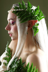 Naklejka premium Beautiful elf girl with floral decor on dark olive background