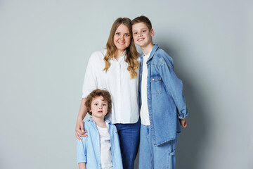 Fototapeta premium Portrait of mother and her sons on grey background