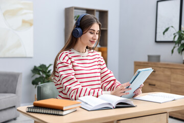 Young student studying with tablet at wooden table indoors