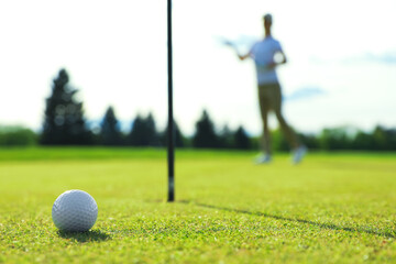 Obraz premium Woman playing golf at green course, focus on ball. Space for text