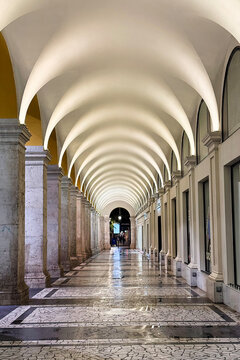 Elegant arched corridor with repeating columns and illuminated ceiling in Galeries Lafayette Nice, France. Symmetrical architecture and perspective in shopping gallery.