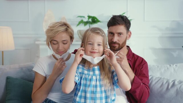 A Family Sitting Together During the Pandemic Wearing Protective Masks in Their Cozy Living Room