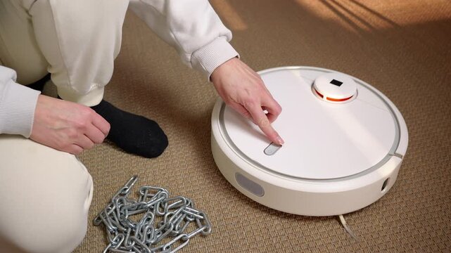 Person breaking free from chains activating a cleaner. Symbolic representation of liberation from domestic chores as a person removes chains from their wrists and turns on a robot vacuum cleaner