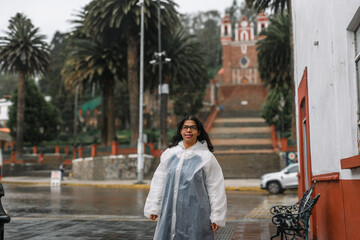 Obraz premium Hispanic Woman in Raincoat Exploring a Historic Mexican Town (Metepec) in the Rain