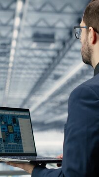 Vertical video Engineer man reviewing semiconductors smart factory schematics with laptop. Manager oversees integrated circuits infrastructure layouts using EDA software on notebook in industry 4.0
