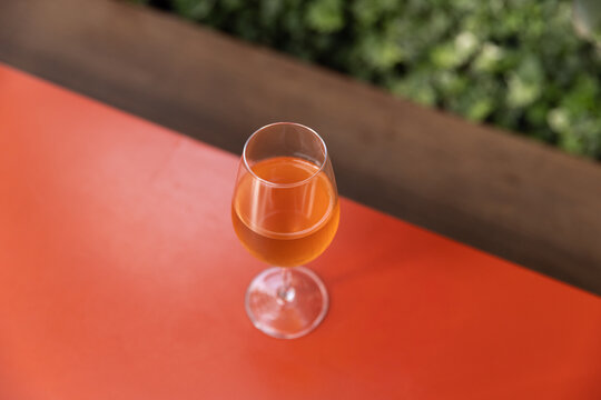 Top down shot of orange wine on bright red table with lush plants 