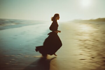 Fototapeta premium Girl in elegant black dress sprinting on sunlit beach with soft focus and film grain aesthetic