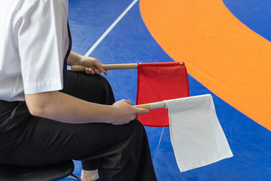 Martial arts referee holding red and white scoring flags