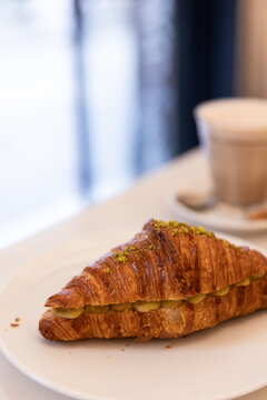 close up shot of pistachio croissant in cafe with coffee in the background