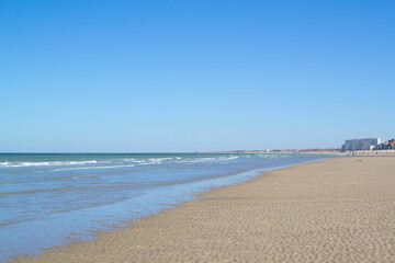 Fototapeta premium Dunkirk beach, Plage Dunkerque, promenade near the sea, coastline, sand, dunes, Malo-les-Bains, France, La Manche, people walking far away, a large beach known from the Second World War