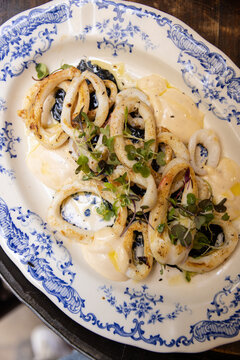 dish of Catalonian squid with house made aioli, squid ink, and micro greens on traditional ceramic plate