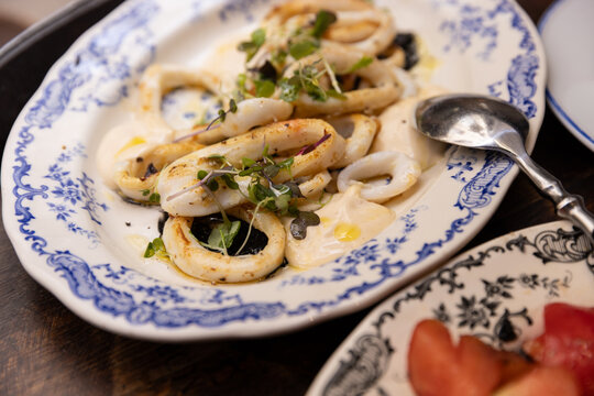 dish of Catalonian squid with house made aioli, squid ink, and micro greens on traditional ceramic plate