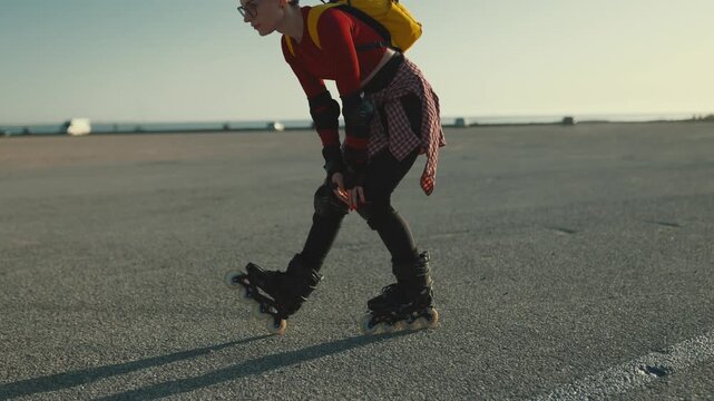 Young woman skating on asphalt at sunset