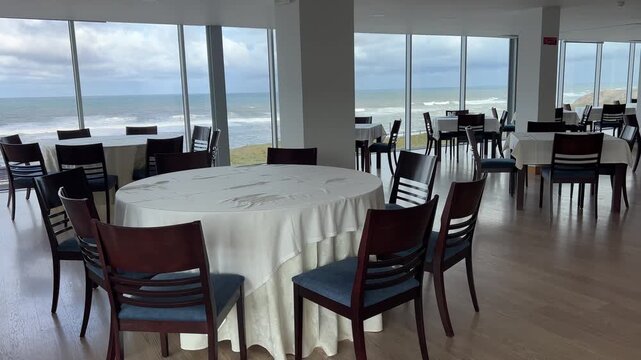 Restaurant table by panoramic window with ocean view, elegant dining scene