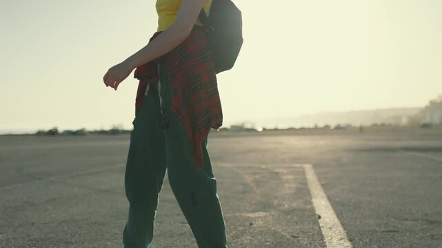 Young woman longboarding on an empty road at sunset