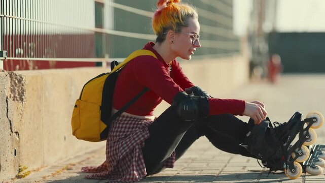 Young woman with colored hair putting on rollerblades
