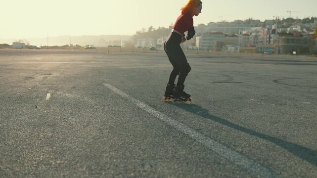 Woman with red hair roller skating backwards on asphalt