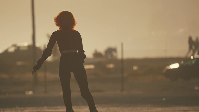 Silhouette of woman roller skating at sunset