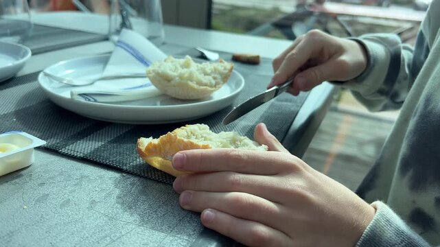 Spreading butter on bread at dining table, close up meal scene