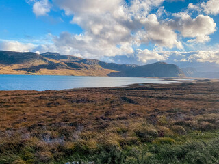 Obraz premium Calm Waters Reflect Distant Peaks. Tranquil Moorland Scene With Cloudy Sky And Mountain Reflections