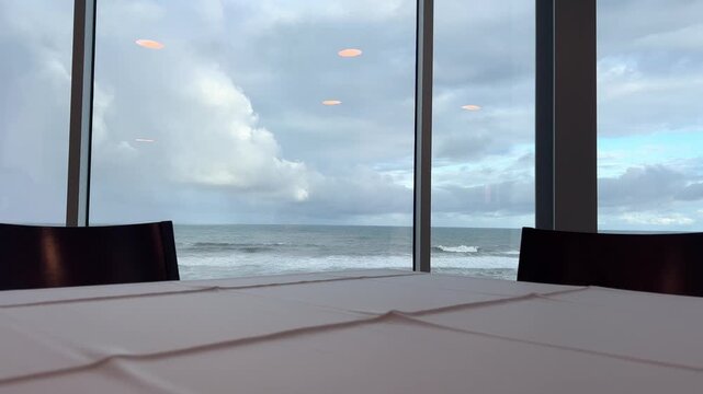Table by seaside window in restaurant, calm ocean view interior