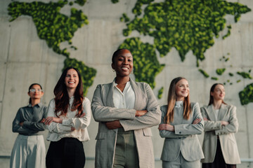 Fototapeta premium Diverse businesswomen team standing with crossed arms in office, global leadership and environmental responsibility concept