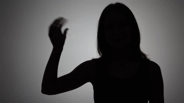 Silhouette of a woman waving her hand as if greeting or saying goodbye