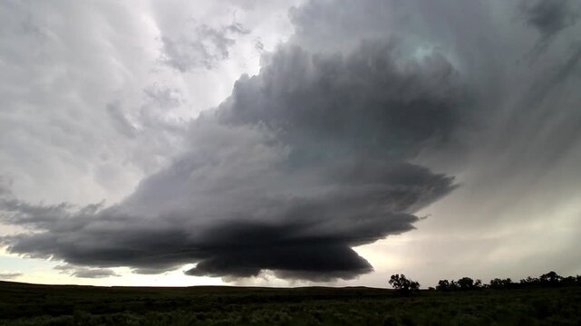 A supercell storm updraft with a corkscrew appearance spins in the sky over a flat landscape. 