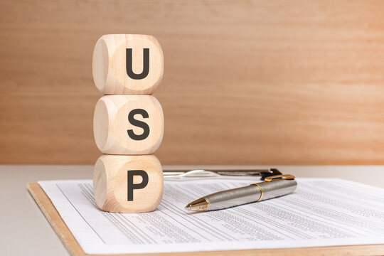 Wooden blocks stack with USP Unique Selling Proposition business marketing concept, pen, and documents.