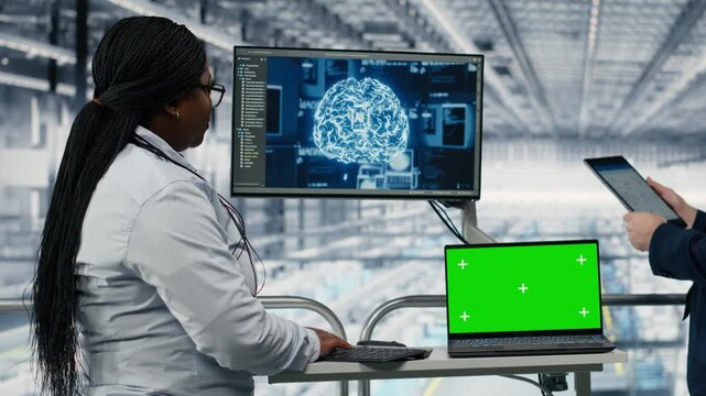 Green screen mockup laptop and AI used by businesspeople in PCB factory to develop roadmap. Directors use neural network and chroma key notebook to develop semiconductor engineering tech, camera B