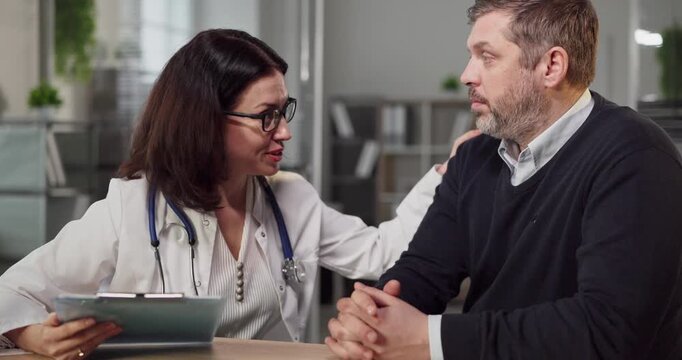 Doctor and patient in clinic consultation discussion. Woman doctor listens as man explains symptoms and offers medical advice in a healthcare office. Clear concept of patient centered care.