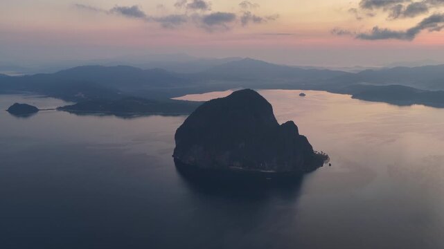 Sunrise silhouettes dramatic limestone islands in Bacuit Bay, El Nido, at sunset. This area in the Philippines is a popular vacation destination due to its coral reefs, beaches, and hidden lagoons.
