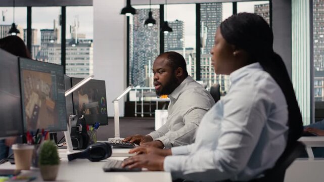 Black employees team using architectural CAD software for modern layout design, 3D rendering program on dual monitors. Architectural floor plan with tools and assets used for remodeling.