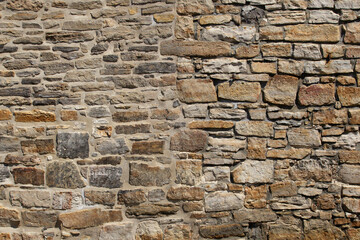 Fototapeta premium Rough stone wall with varied sizes and natural hues. Stones form a sturdy, weathered surface. Textures show age and craftsmanship. Ideal for architectural backgrounds or historical contexts