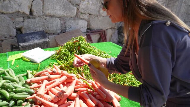 Woman choosing fresh organic vegetables at Sigacik Castle local street market
